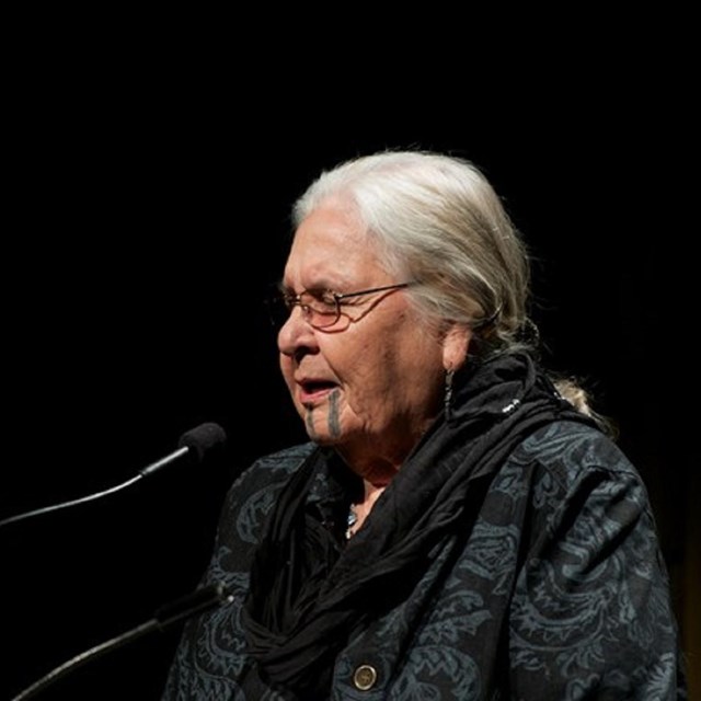 Woman speaking against black background